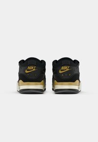 Mustmust mõjutavad mustad ja kuldsed Nike Airi tossud, millel on reljeefne must ülemine osa, pehmendatud krae ja kuldsed aktsendid vahejaotusel ja brändingul.
