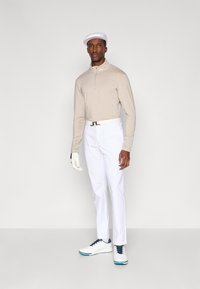 Meeste golfiriietus, mis sisaldab beeži pika varrukaga polo, valgeid pükse ja valgeid jalanõusid siniste aktsentidega. Valge lame müts ja kindad lõpetavad välimuse.