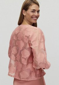 Różowa przezroczysta kurtka o kwiatowej strukturze, z uniesionymi wzorami liści i luźnym krojem. Długie rękawy z lekko ściąganymi mankietami.
