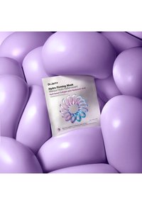 Verpakking van Dr.Jart+ Hydro Firming Mask rustend op gladde, afgeronde, glanzende lavendelkleurige vormen die lijken op opgeblazen kussens of bellen.