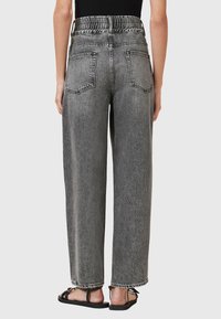 Hoge taille, wijde jeans in vervaagd zwart denim. Voorzien van een elastische tailleband en twee achterzakken met contrasterend stiksel.