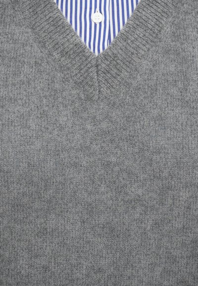 Grau gestrickter V-Ausschnitt-Pullover mit geripptem Muster, über einem blauen und weißen gestreiften Hemd mit Knopfkragen getragen.