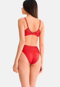 Ensemble de lingerie rouge comprenant un soutien-gorge en mesh transparent avec des bretelles réglables et une culotte haute en mesh transparent, mettant en valeur une texture lisse et brillante.