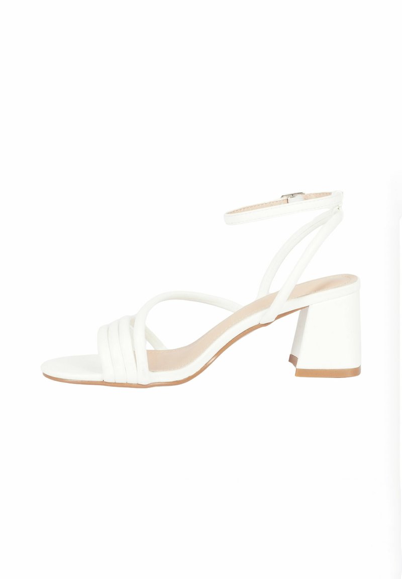 Sandal con tacco bianco e design con punta aperta, dotato di molteplici cinturini e tacco largo. Texture liscia e cinturino regolabile alla caviglia.