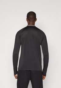 Czarny longsleeve wykonany z gładkiego, lekkiego materiału. Posiada okrągły dekolt oraz rękawy raglanowe, co zapewnia dopasowany krój.