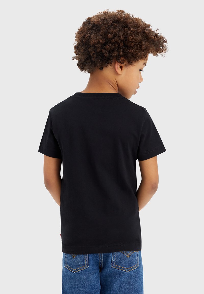 Zwarte T-shirt met korte mouwen en een ronde hals, gemaakt van katoen. Dit toont een eenvoudige achterkant, ingestopt in blauwe denim shorts.