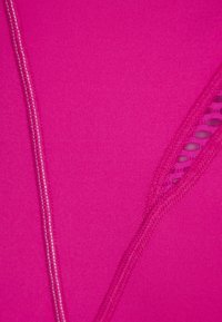 Fuchsia träningskläds tyg med en mjuk textur, med en kontrasterande krämfärgad söm och en utskärning på ena sidan.