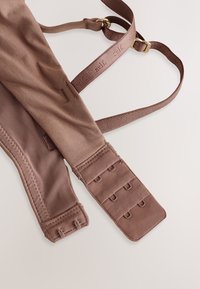 Pruun rinnahoidja reguleeritavate rihmade ja konksude kinnitusdetailidega. Valmistatud siidisest kangast, millel on pehme tekstuur, täiendatud detailse õmblemise ja metallist aksessuaaridega.