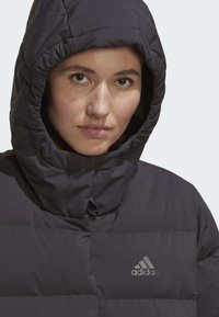 Black padded hooded jacket with a zipper and elastic cuffs, featuring a subtle Adidas logo on the chest. Material appears smooth and insulated.