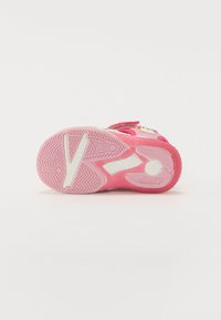 Roosa laste sneakers, millel on tekstuuriga kummitald, Velcro rihmad ja dekoratiivsed aksessuaarid. Omab sakilise tallakujundust haardeks.