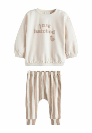 Hellrosa Sweatshirt mit der Aufschrift "just hatched" und einer Enten-Grafik; kombiniert mit beige-weiß gestreiften, gerippten Hosen. Elastischer Bund, lockere Passform.