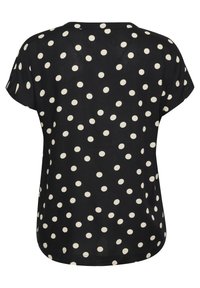 Blusa nera a maniche corte con pois bianchi, con orlo arrotondato, tessuto morbido e vestibilità rilassata. Vista posteriore mostrata.