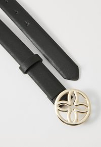 Cintura in pelle nera con texture liscia e una fibbia dorata rotonda, forata, con un design floreale e quattro accenti a forma di petalo.
