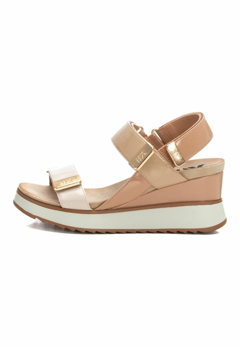 Sandalia de cuña con un acabado de charol rosa claro, acentos dorados, correas ajustables y suela de goma texturizada. Diseño moderno con un tacón grueso.