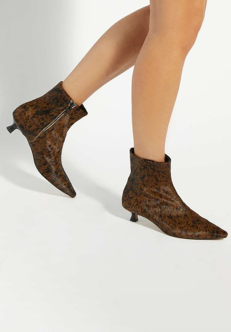 Brown, pointed-toe ankle boots with a textured finish, featuring a side zipper and a low kitten heel. The pattern resembles animal print.
