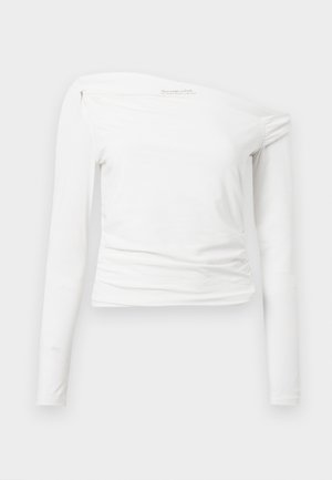 Top alb cu mâneci lungi, design off-shoulder, țesătură netedă, detalii pliate la umăr și o siluetă ajustată.
