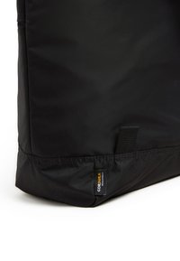 Svart nylonväska med en texturerad yta, robust sömnad och en distinkt CORDURA®-etikett i underkanten. Minimalistisk design, utan dekorationer.