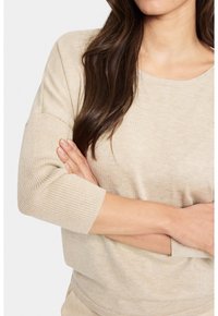 Beiger, gerippter Strickpullover mit 3/4-Ärmeln und Rundhalsausschnitt, der einen lockeren Schnitt und eine weiche Textur bietet.