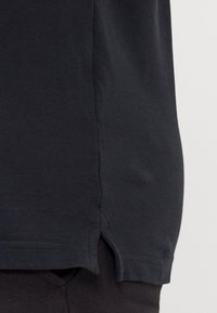 Mustat puuvillapaita, jossa on sivuhalkiot hemline. Sujuva tekstuuri klassisella pyöreällä kaula-aukolla ja lyhyillä hihoilla.