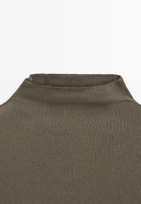 Ribbed high-neck top in dark olive green. Features a vertical texture and a fitted silhouette with a subtle stretch for comfort.