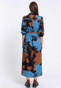 Sukienka maxi w niebiesko-brązowo-czarny kwiatowy wzór, wykonana z gładkiego materiału. Posiada długie rękawy, pasek w talii i luźny krój.