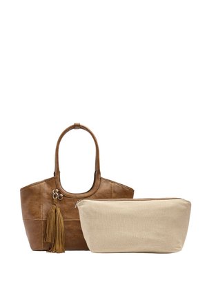 Brązowa skórzana torba typu tote z ozdobą z frędzli obok beżowej materiałowej saszetki na suwak na białym tle.