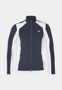Navy and white athletic jacket with a high collar, full zipper, long sleeves, and zippered side pockets; features logo on chest.