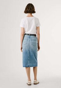 Denim midi kjol med en ombre-effekt, ljusblå som övergår till mörkare blå, har bakfickor och ett brunt bälte. Kombinera med en åtsittande vit t-shirt.