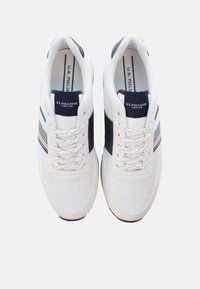 Sneakers bianchi in rete con dettagli blu navy, lacci piatti e un design a righe sul lato. Presentano una suola imbottita e un'etichetta con il marchio sulla linguetta.