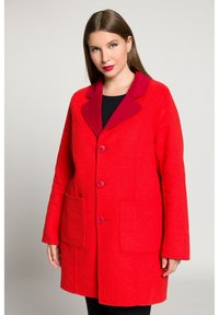 Cappotto in misto lana rosso con colletto bordeaux a contrasto, chiusura con cinque bottoni e due tasche frontali. Tessuto morbido, vestibilità sartoriale.