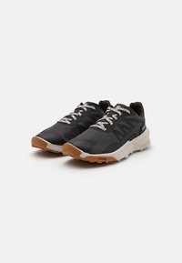 Black athletic shoes with mesh upper, reflective laces, and brown outsole. Features a cushioned heel and textured accents for grip.