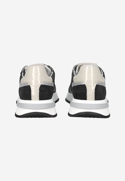 Pair of black and beige sneakers with white and gray thick soles, viewed from the back against a white background.