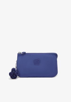 Fioletowy worek z zamkiem błyskawicznym z trwałego materiału, z okrągłym logo i futrzanym fioletowym breloczkiem przymocowanym do srebrnego kółka.