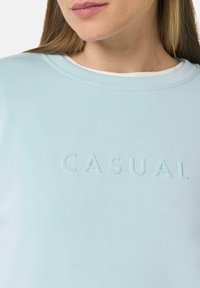 Lichtblauwe sweatshirt met een ronde hals, voorzien van een textuurprint van "CASUAL". Gladde katoenstof, minimalistisch ontwerp en subtiele stiksels.