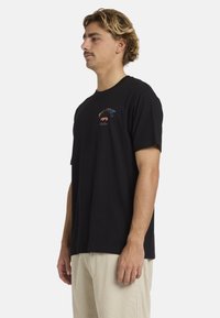Zwarte katoenen t-shirt met korte mouwen, ronde hals, versierd met een kleurrijk geborduurd logo op de borst en een casual pasvorm.