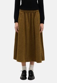 Jupe midi marron texturée avec une taille froncée et des poches latérales, associée à des chaussures noires et des chaussettes crème. Jambes entièrement visibles.