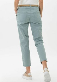 Lichtblauwe, cropped broeken met een soepele textuur, voorzien van achterzakken, een tailleband met riemlussen, en gecombineerd met beige sneakers.