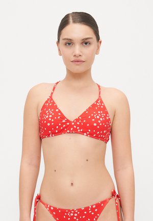 Rdeči bikini z belim cvetličnim vzorcem. Zgornji del ima trikotno obliko in tanke naramnice; spodnji del ima stranske zaveze in podoben cvetlični vzorec.