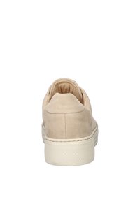 Beige suede sneaker met een ronde neus, gevoerde kraag en een dikke, geprofileerde off-white rubberen zool. De achterkant toont een egale stiknaad.