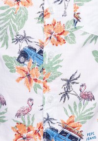 Koszula z krótkim rękawem na białym tle z żywymi wzorami kwiatowymi i tropikalnymi, w tym flamingi i niebieski pojazd, z białymi guzikami.