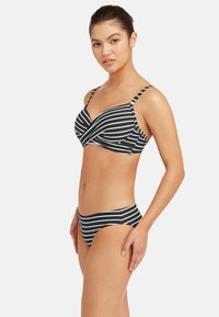 Czarny i biały bikini w paski z topem z zapięciem z przodu, regulowanymi ramiączkami i klasycznymi majtkami o średnim stanie. Miękka tkanina, gładka tekstura.