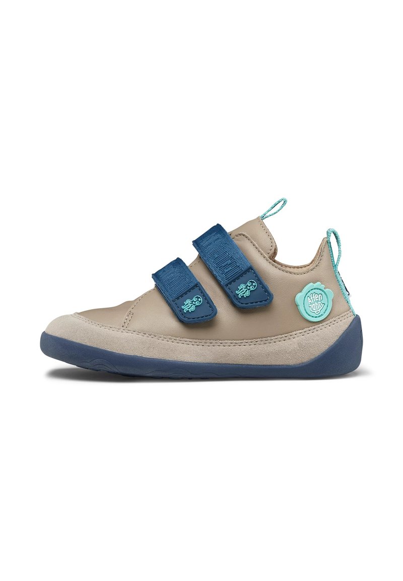 Beige leather shoe featuring two blue Velcro straps, a textured detailing, and a blue rubber sole with a circular logo accent on the side.