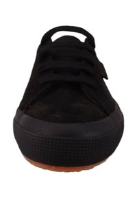 Czarne zamszowe sneakersy z okrągłym noskiem, płaską czarną gumową podeszwą i czarnymi sznurówkami na górze. Podeszwa ma teksturowany wzór po bokach.