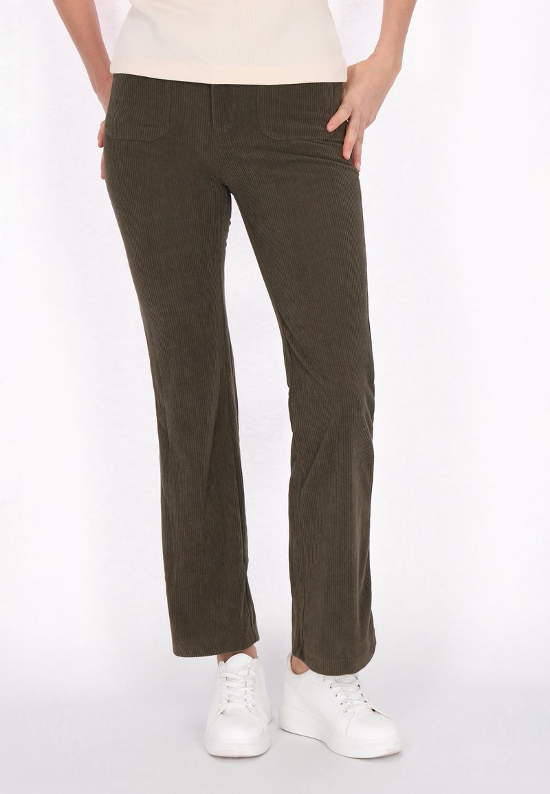 Bruine corduroypantalon met een rechte pijpdesign, voorzakken en een zachte textuur, gecombineerd met witte sneakers.