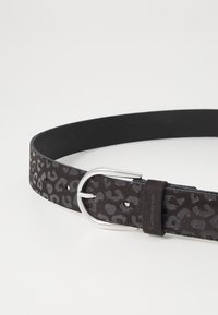 Svart leopardmönstrad mockabälte med ett spänne i silvermetall, med en slät yta och flera justeringshål.