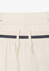 Pantalones cortos beige con una cinturilla texturada con acentos en navy, cordones elásticos y una tela suave con detalles plisados.