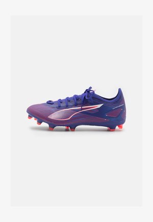 Lila Fußballschuh mit strukturiertem Finish, ausgestattet mit pinken Akzenten, sechs eckigen Stollen und einem stromlinienförmigen Design. Die Schnürsenkel sind vorne gebunden.