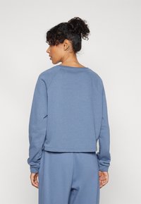 Sudadera azul con un ajuste relajado, mangas raglán y un dobladillo corto. Hecha de una tela suave, con un escote tipo crew y puños acanalados.