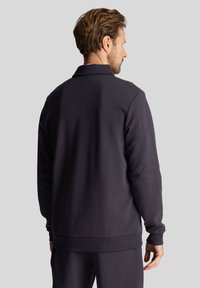 Donkergrijze pullover met een textuurstof, geribde manchetten en zoom, en een kraag. Heeft een ontspannen pasvorm en is van achteren te zien.
