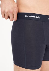 Boxers de color azul marino con una cinturilla gruesa que presenta la marca "Resteröds" en texto blanco. Tela suave con un diseño ajustado.